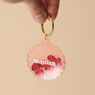 Porte-clés en plexiglass transparent et coloré rose sur anneaux dorés. Il a une forme de cercle festonné et contient 8 mini découpes en forme de cœur rouge qui bougent librement à l’intérieur. Ces découpes sont gravées de mots associés à la maternités «  tendresse, amour, bisous.. »